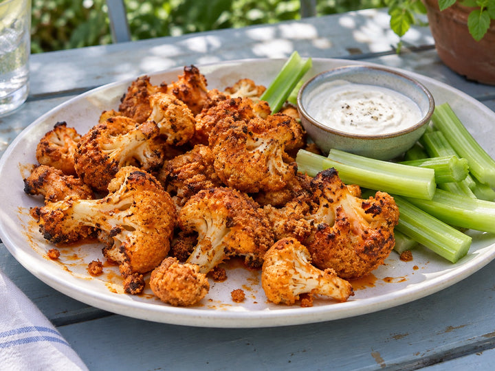 Buffalo cauliflower with celery and dip on a backyard table
