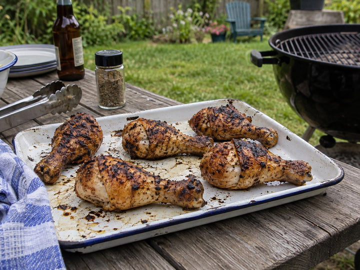 Grilled chicken drumsticks on an enamel tray outdoors