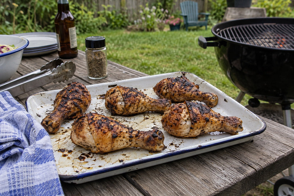 Grilled chicken drumsticks on an enamel tray outdoors