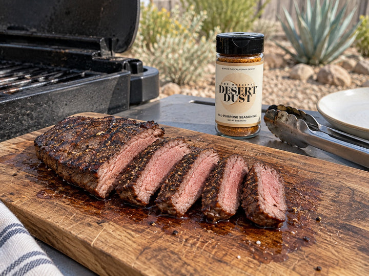 Sliced grilled flat iron steak on a board beside a backyard grill