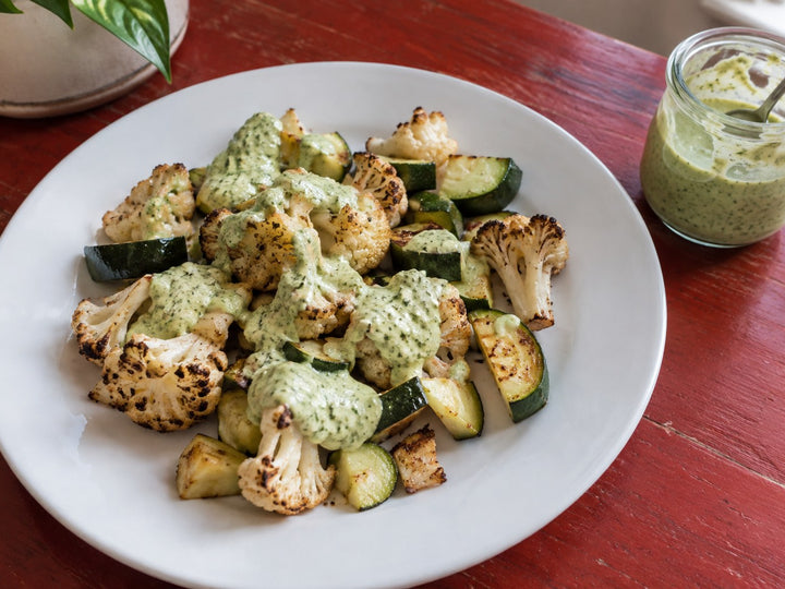 Poblano cream sauce spooned over roasted cauliflower and zucchini on a white plate