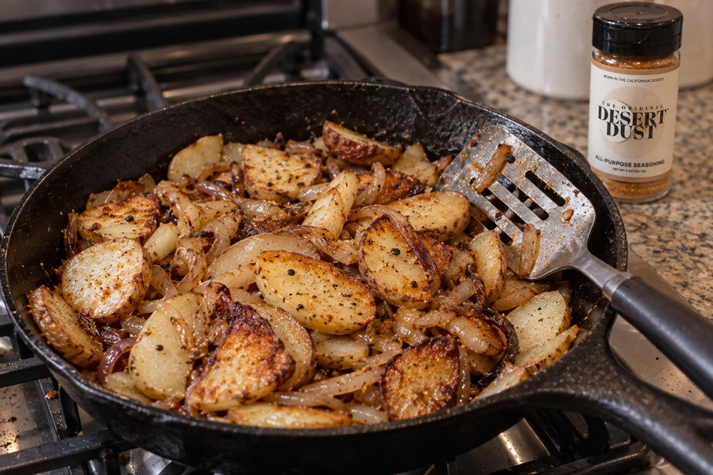 Fried potatoes and onions in a cast iron skillet beside Original Desert Dust