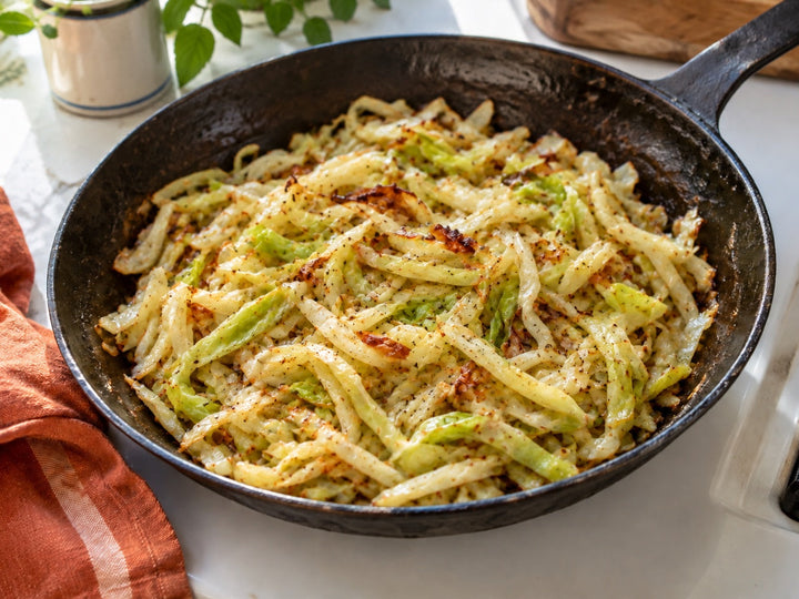 Thin sauteed cabbage ribbons with browned edges in a black skillet.