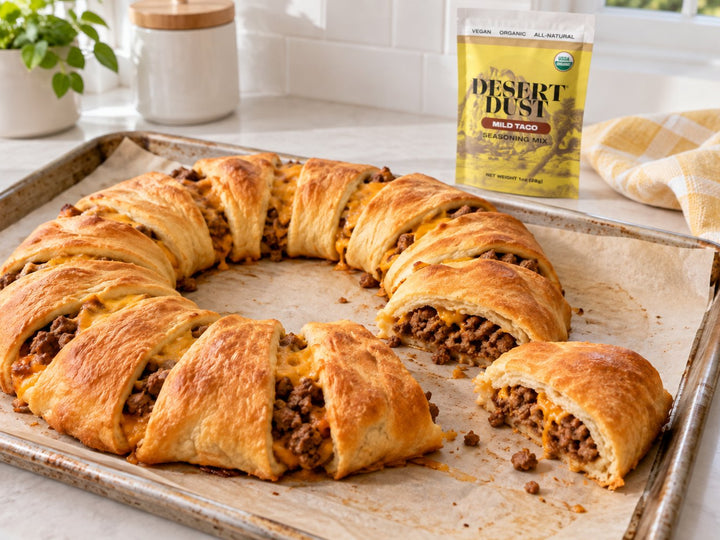 Golden crescent taco ring with beef and cheddar on a baking tray, with Mild Taco seasoning nearby.