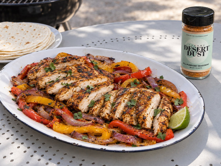Grilled chicken breast slices with red and yellow peppers, red onion and flour tortillas beside a Savory Desert Dust jar.