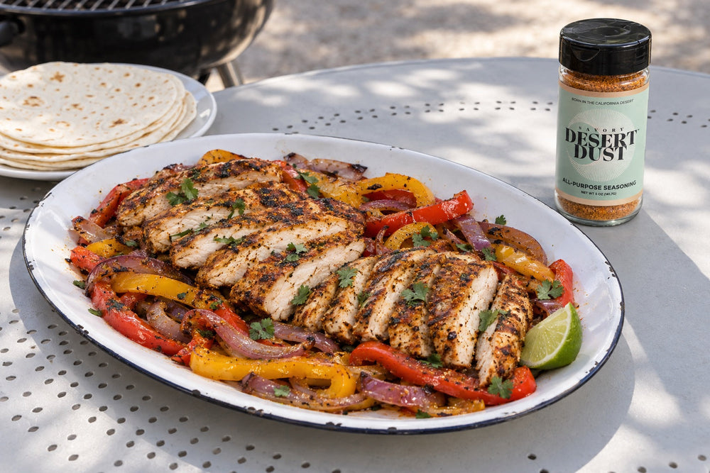 Grilled chicken breast slices with red and yellow peppers, red onion and flour tortillas beside a Savory Desert Dust jar.