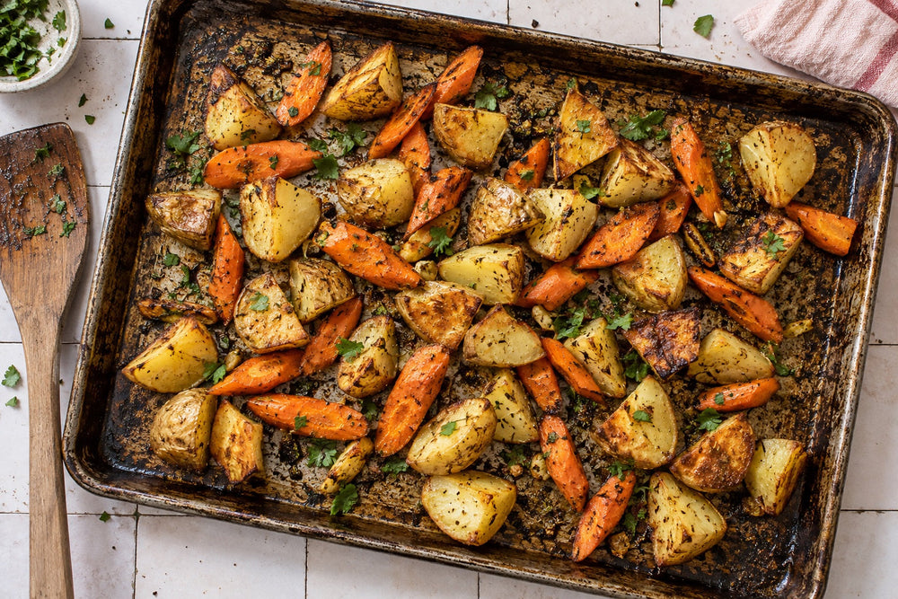 Homemade roasted potatoes and carrots on a baking sheet