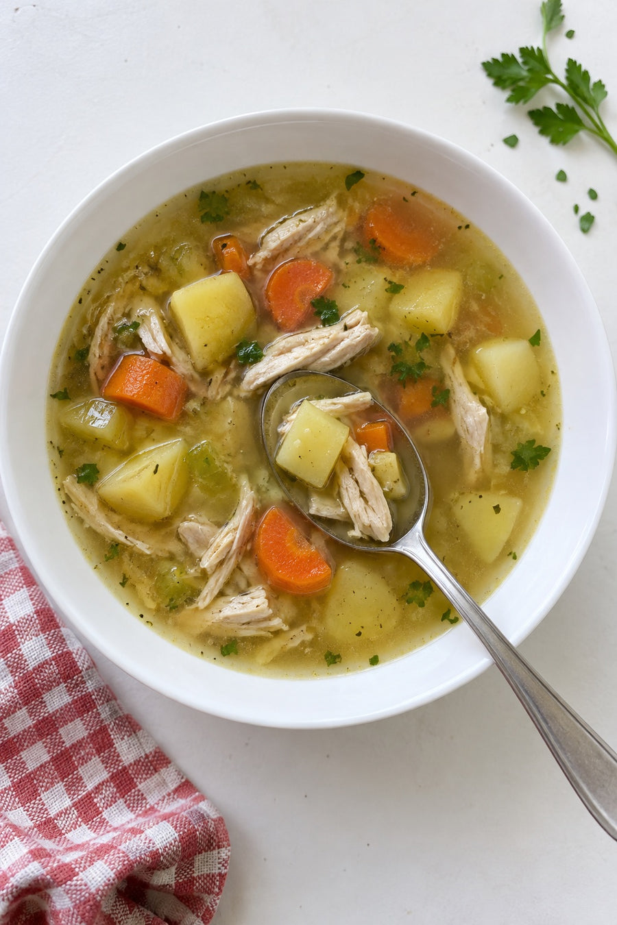 Overhead view of chicken potato soup with a spoonful of potato and shredded chicken.