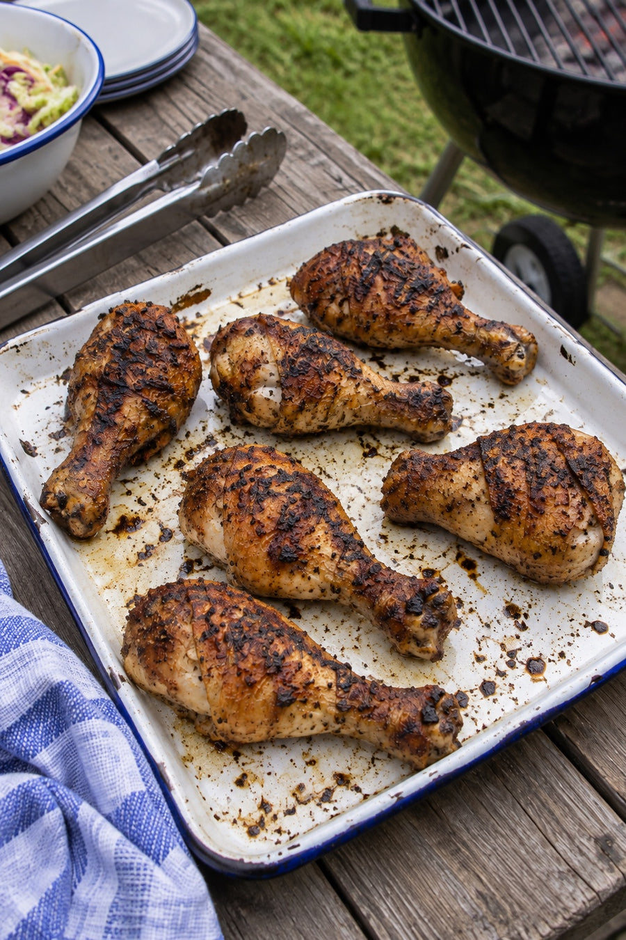 Grilled chicken drumsticks on an enamel tray outdoors