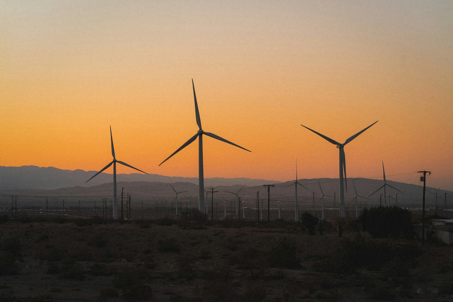 Desert wind turbines beneath an orange sunset