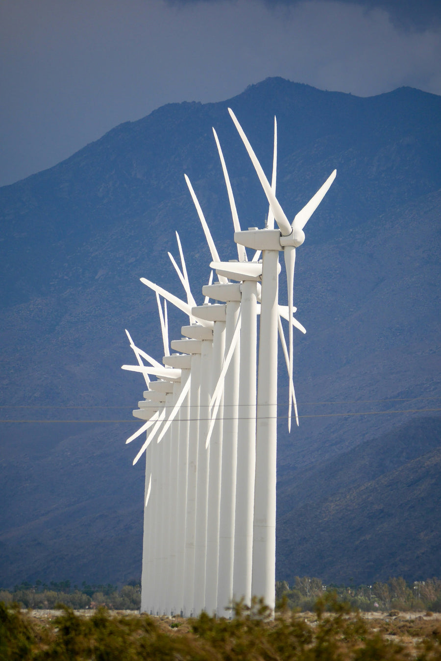 White wind turbines against blue desert mountains