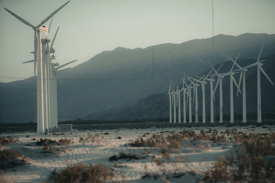 A row of turbines beneath hazy desert ridges