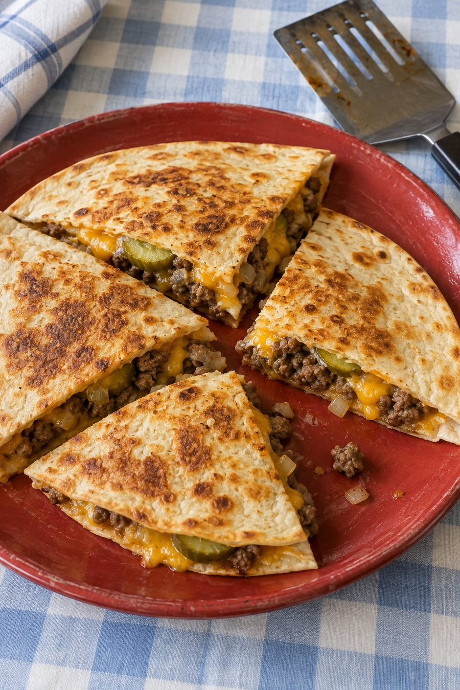 Toasted cheeseburger quesadilla wedges with ground beef, cheddar and sliced dill pickles.
