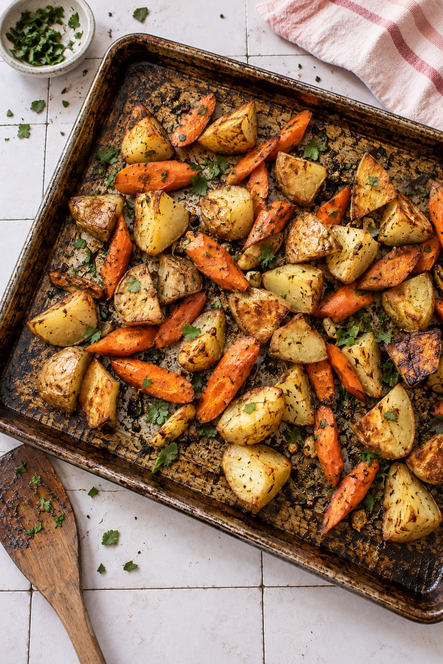 Homemade roasted potatoes and carrots on a baking sheet