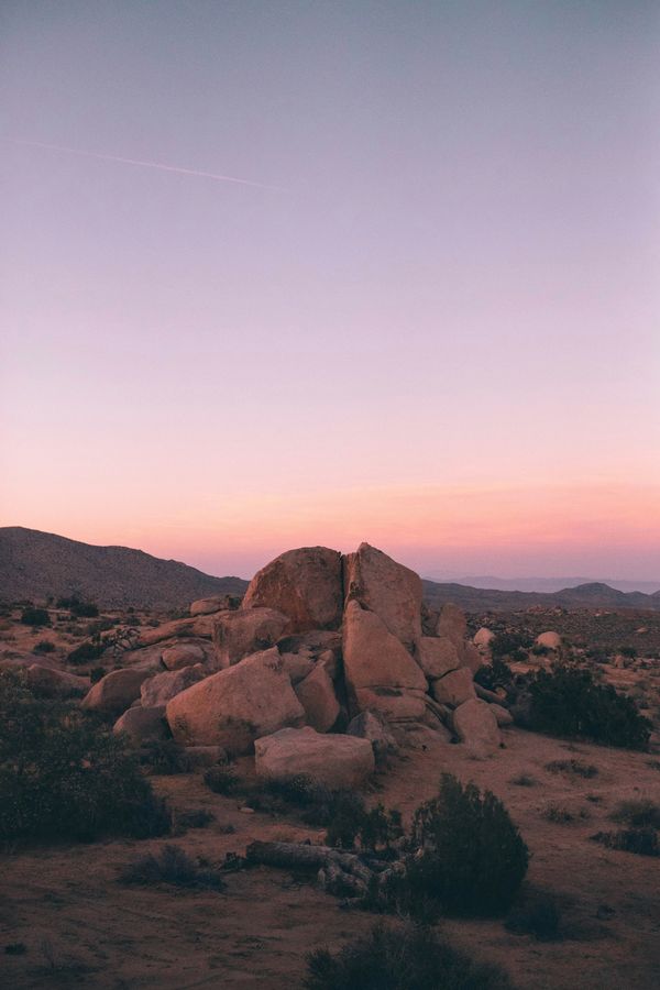 Desert boulders beneath a pale pink and lavender sunset sky.