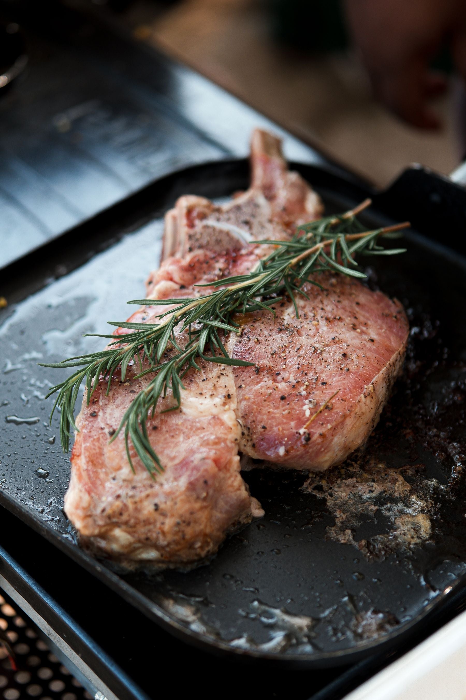 Seasoned pork chop in a pan with rosemary